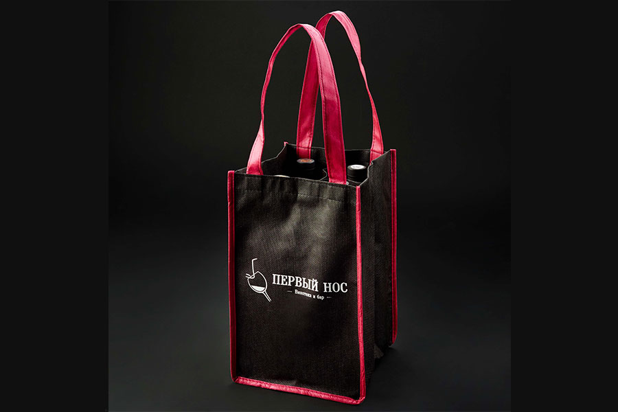 промо сумка из черного спанбонда с ручками и окатновкой красного цвета, внутри перегородки для четырех бутылок, одноцветный логотип белого цвета